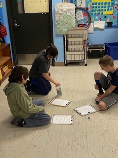 Fourth Grade: Keegan, Robby, and Kayden mastering the bottle flip activity in math class! 