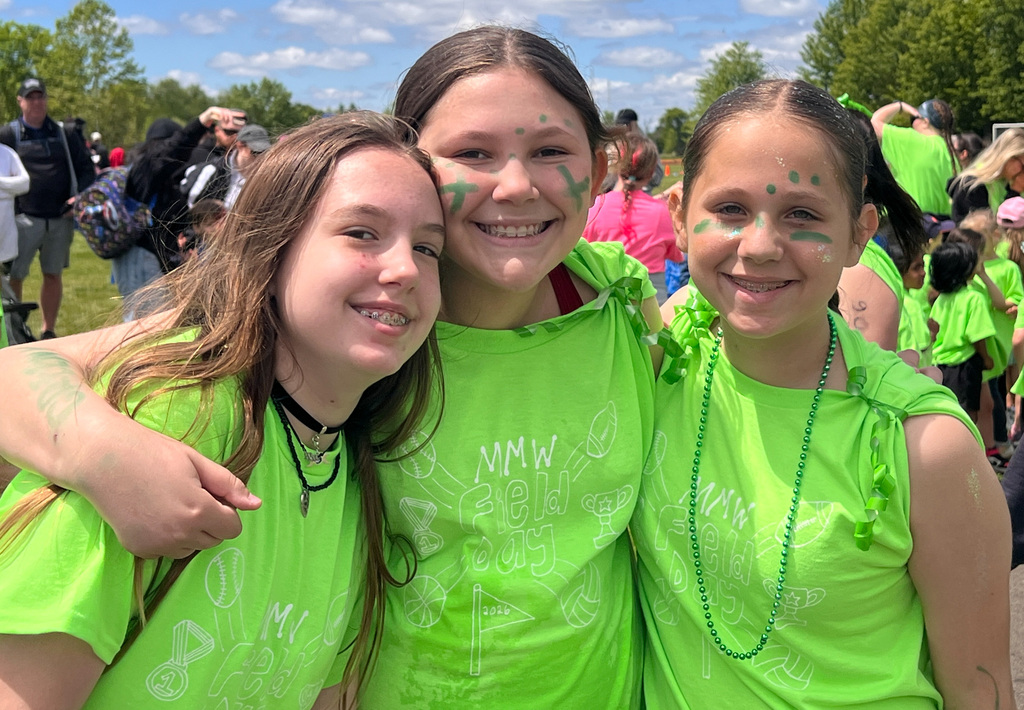 three students smiling with their field day gear on