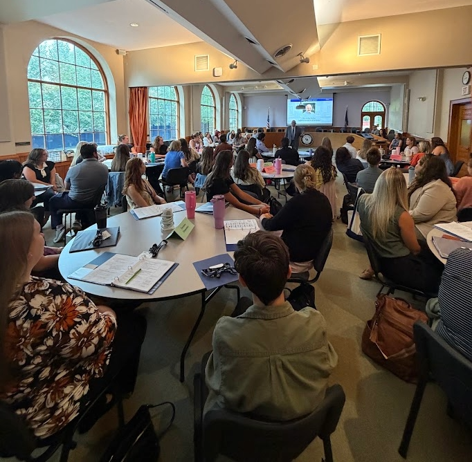 teachers sitting around round tables listening to professional development discussion