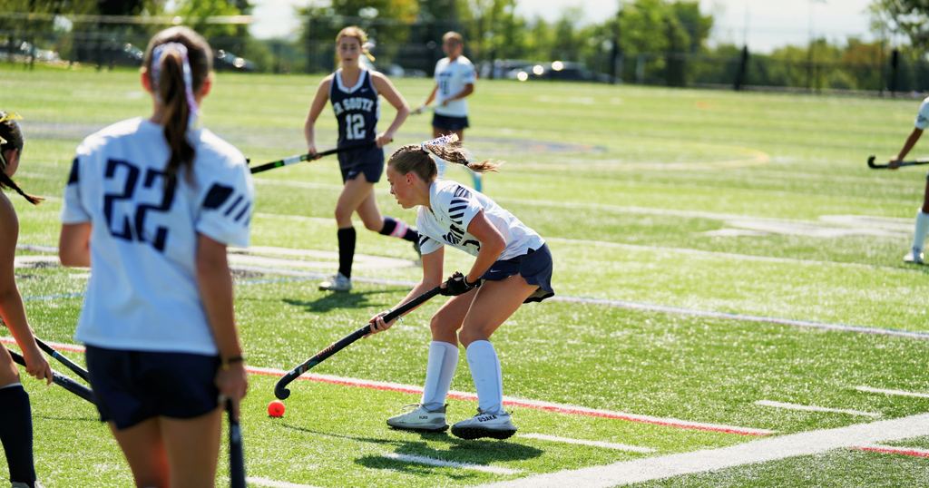field hockey players on the field trying in motion on a grass field