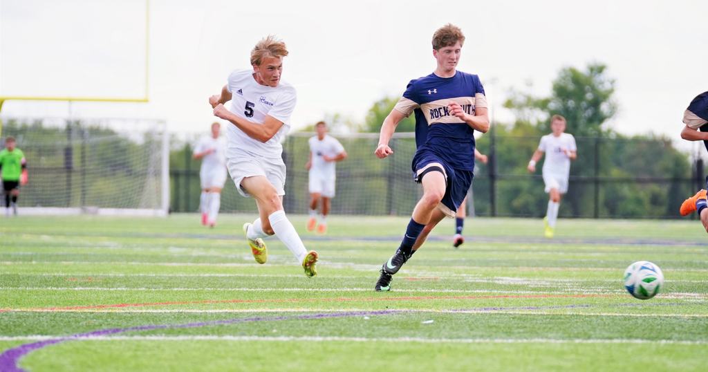 two soccer players in pursuit of the soccer ball on a green field