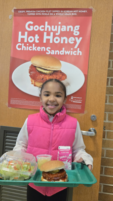 student with pink vest with a lunch tray