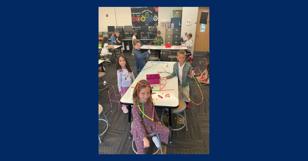a classroom full of students smiling in front of STEAM project that they created