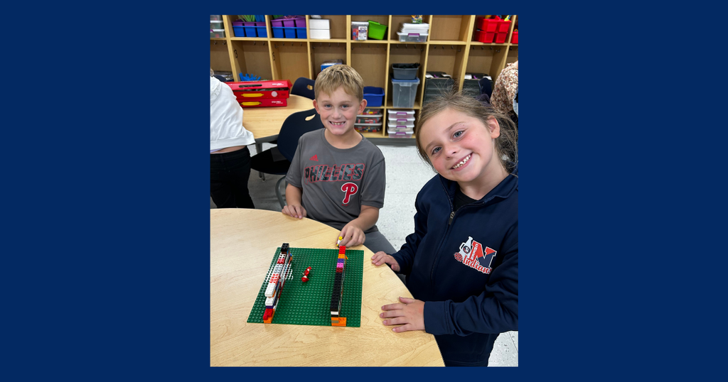 two students buiding Lego STEAM project while smiling to the camera