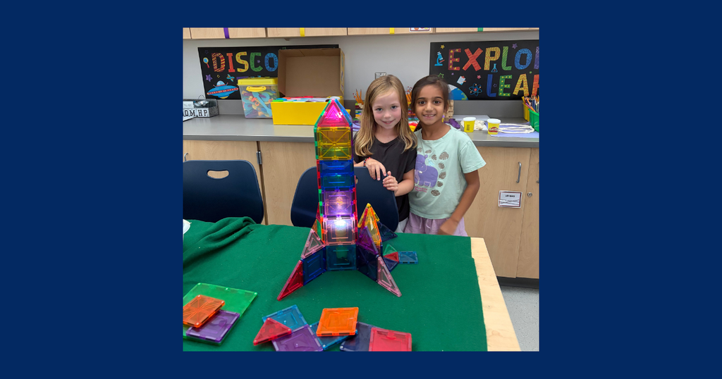 two girls standing in front of a magnitiles rocket