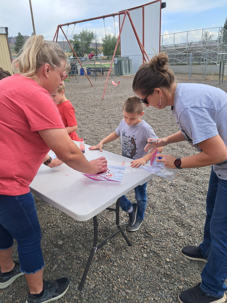 adults help a child tie dye