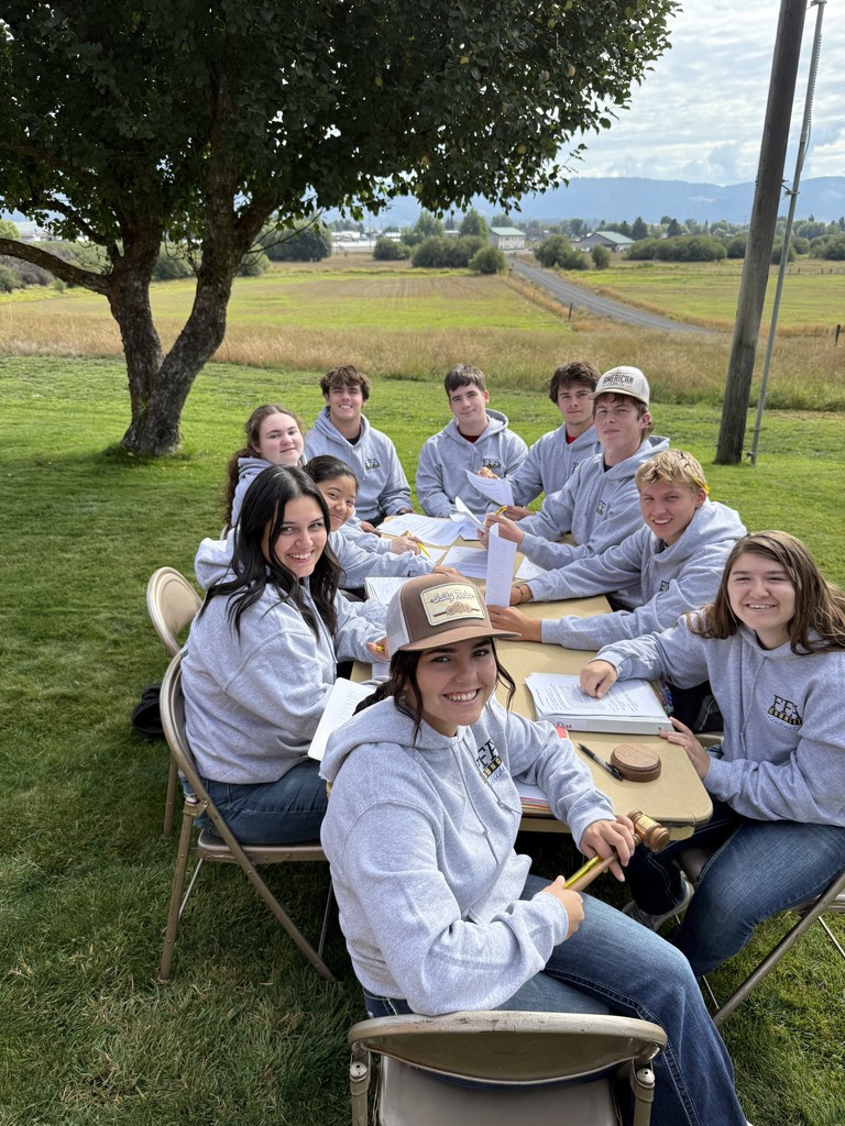 students sit outside at table