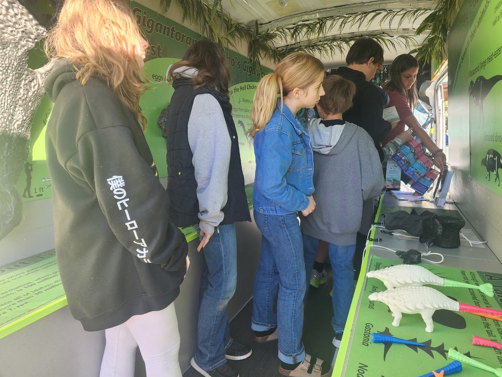 students stand by table with dinosaur relics