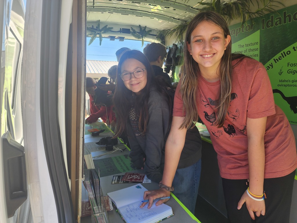 students stand by table with dinosaur relics
