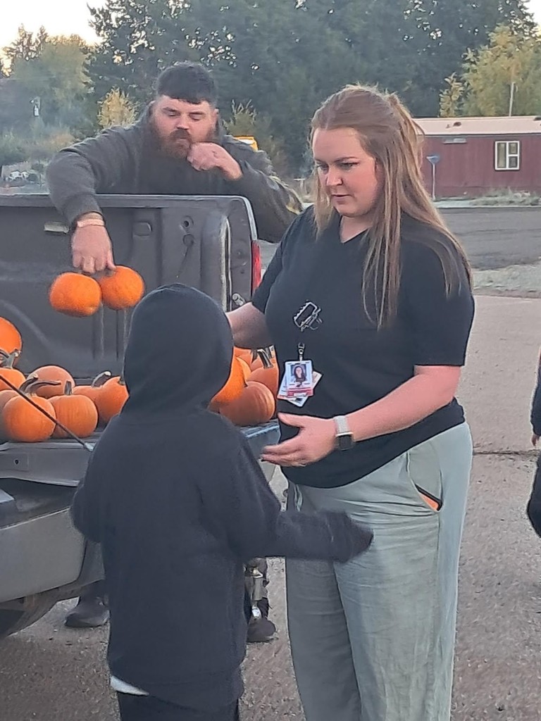 woman hands pumpkin to child
