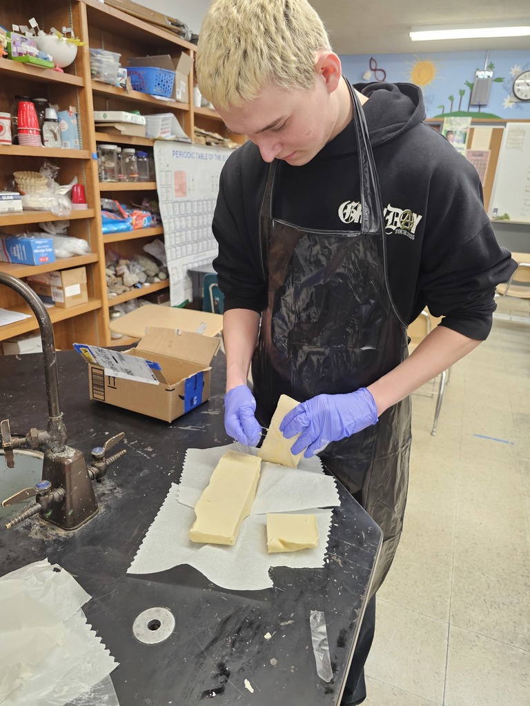 student in apron and gloves handles soap