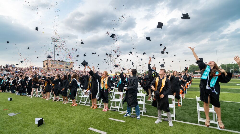 High School graduates throwing their caps into the air at graduation.