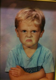 boy with a scowl and arms crossed