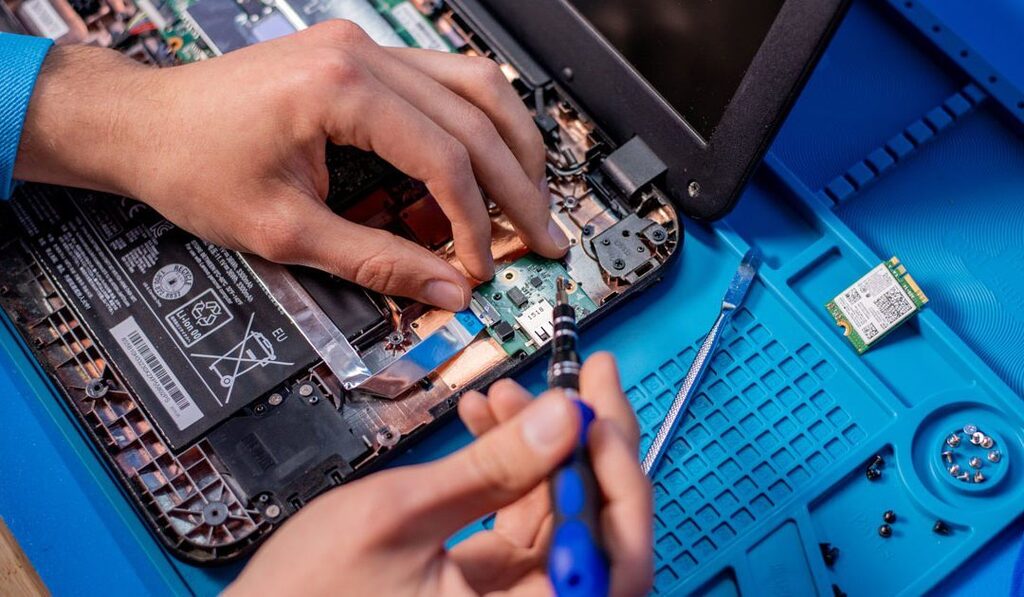 Chromebook opened and being repaired by hands and some tools