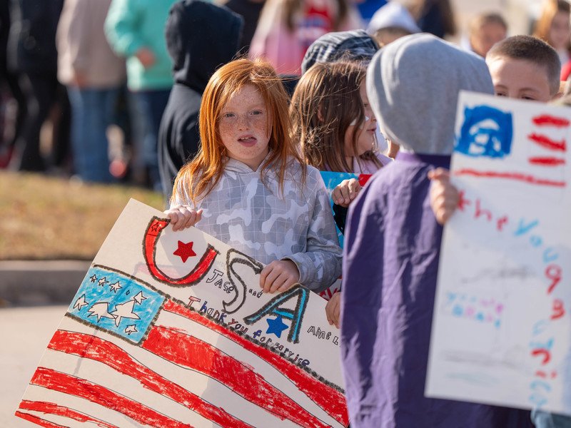Teacher and students at a parade with signs and flags