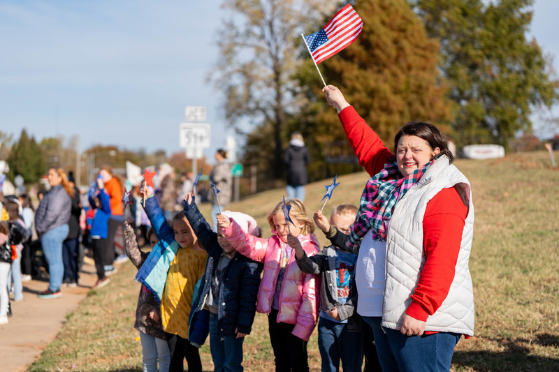 Teacher and students at a parade with signs and flags