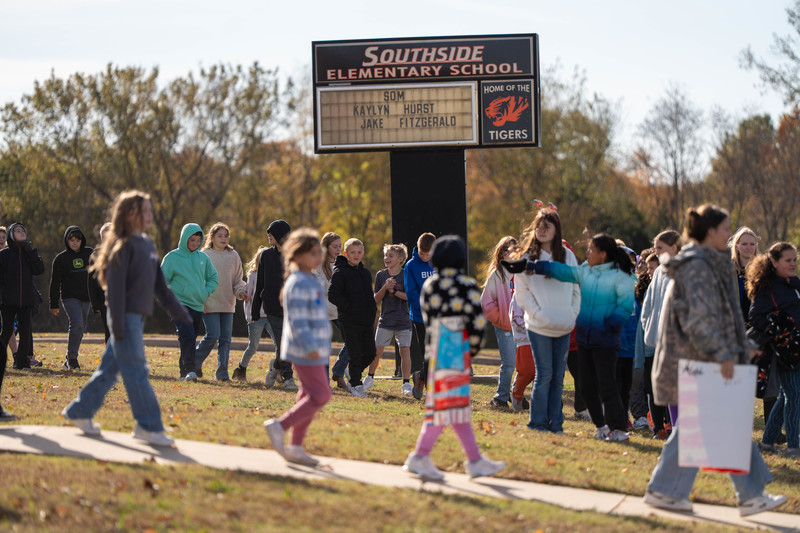 Teacher and students at a parade with signs and flags