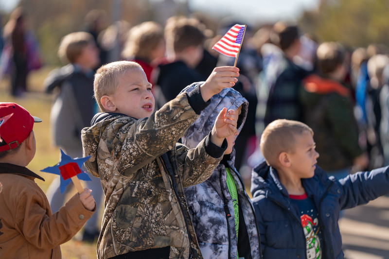 Teacher and students at a parade with signs and flags