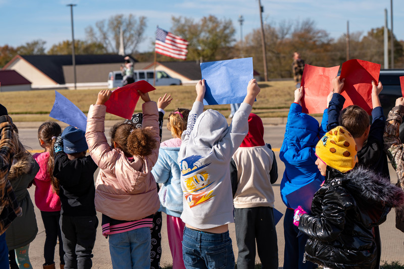 Teacher and students at a parade with signs and flags