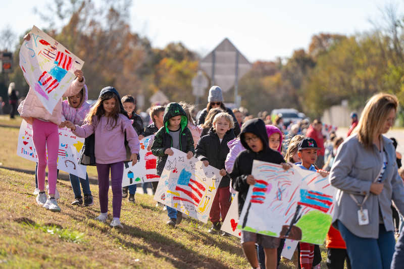 Teacher and students at a parade with signs and flags