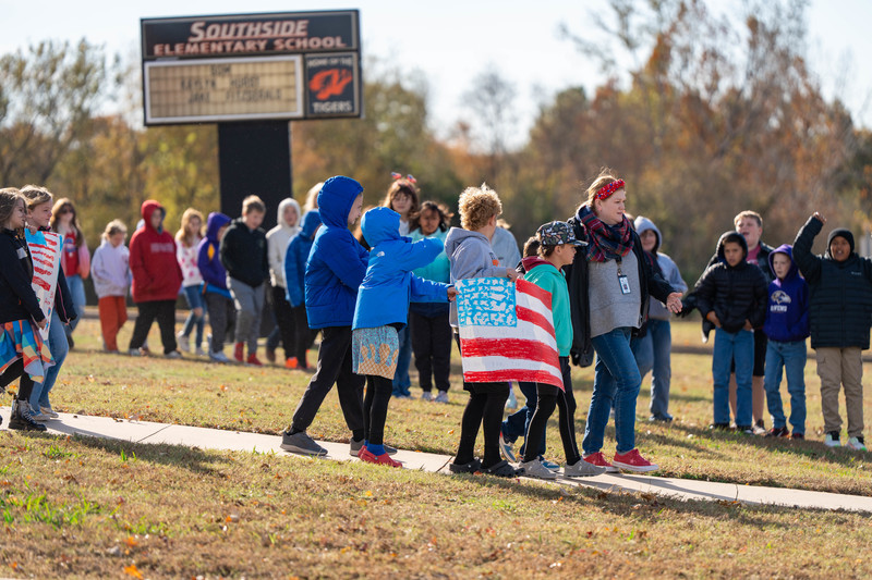 Teacher and students at a parade with signs and flags