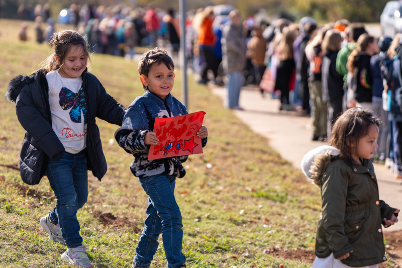 Teacher and students at a parade with signs and flags