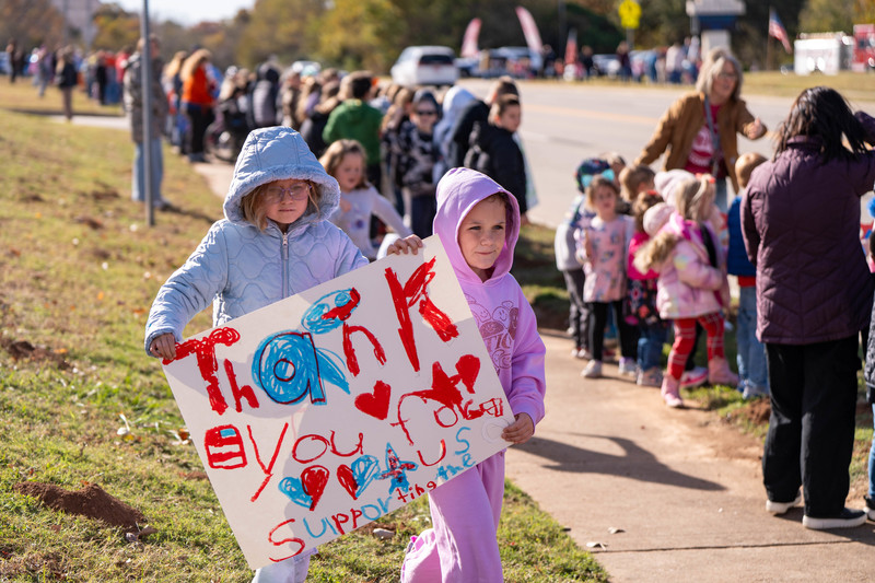 Teacher and students at a parade with signs and flags