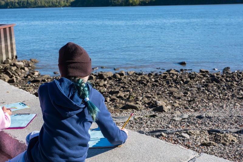student looking out at river taking notes