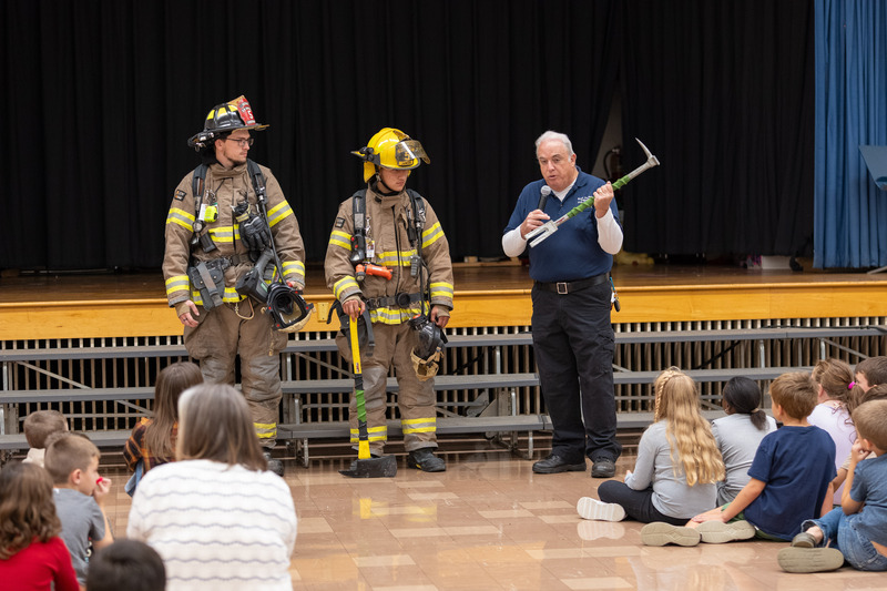 firefighters showing off tools to students