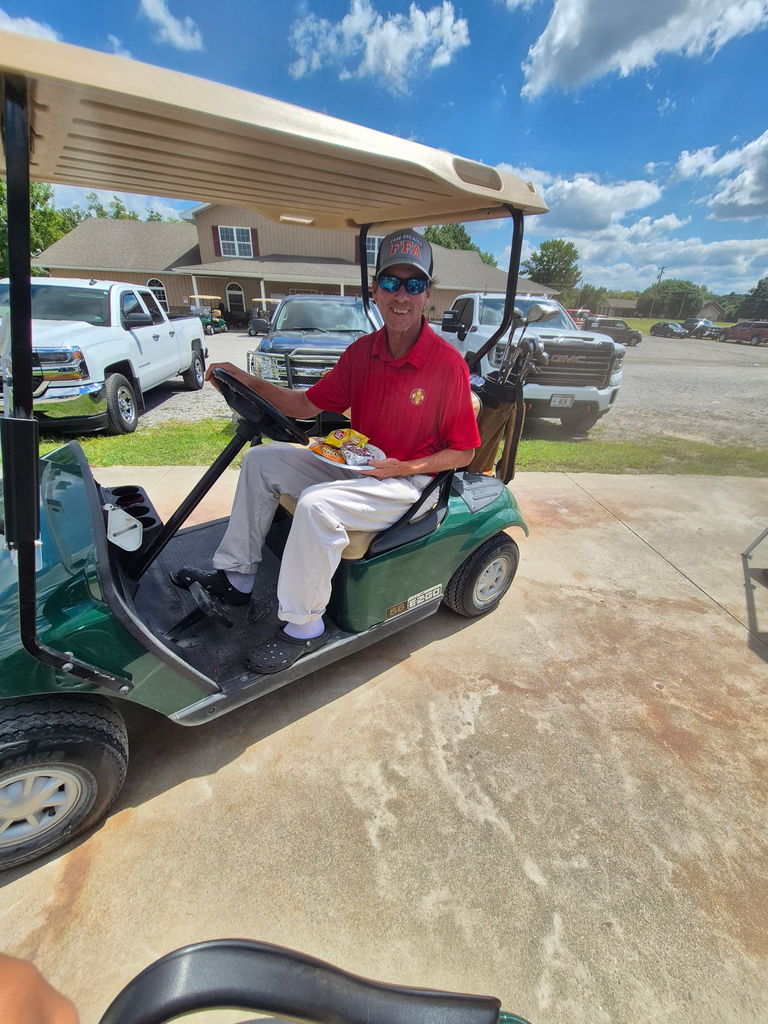 man in a red shirt and white pants in a golf cart
