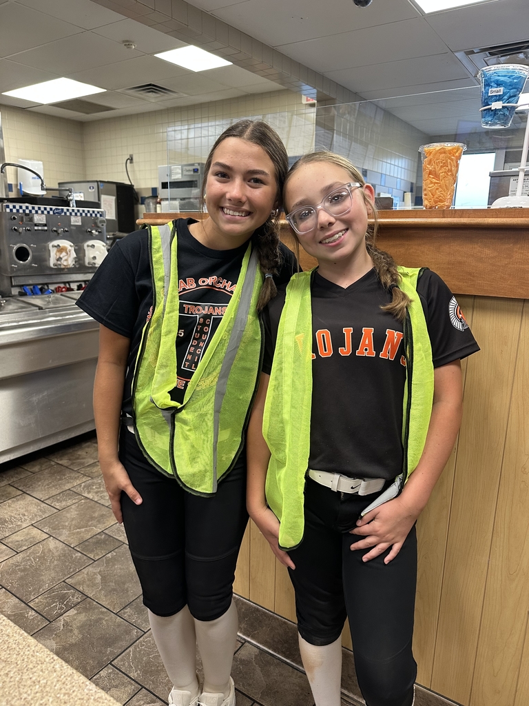 2 junior high females wearing bright yellow vests standing at a restaurant