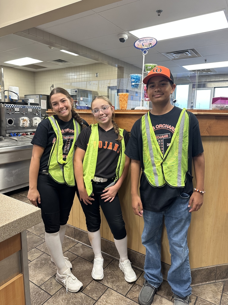 3 junior high students wearing bright yellow vests standing at a restaurant