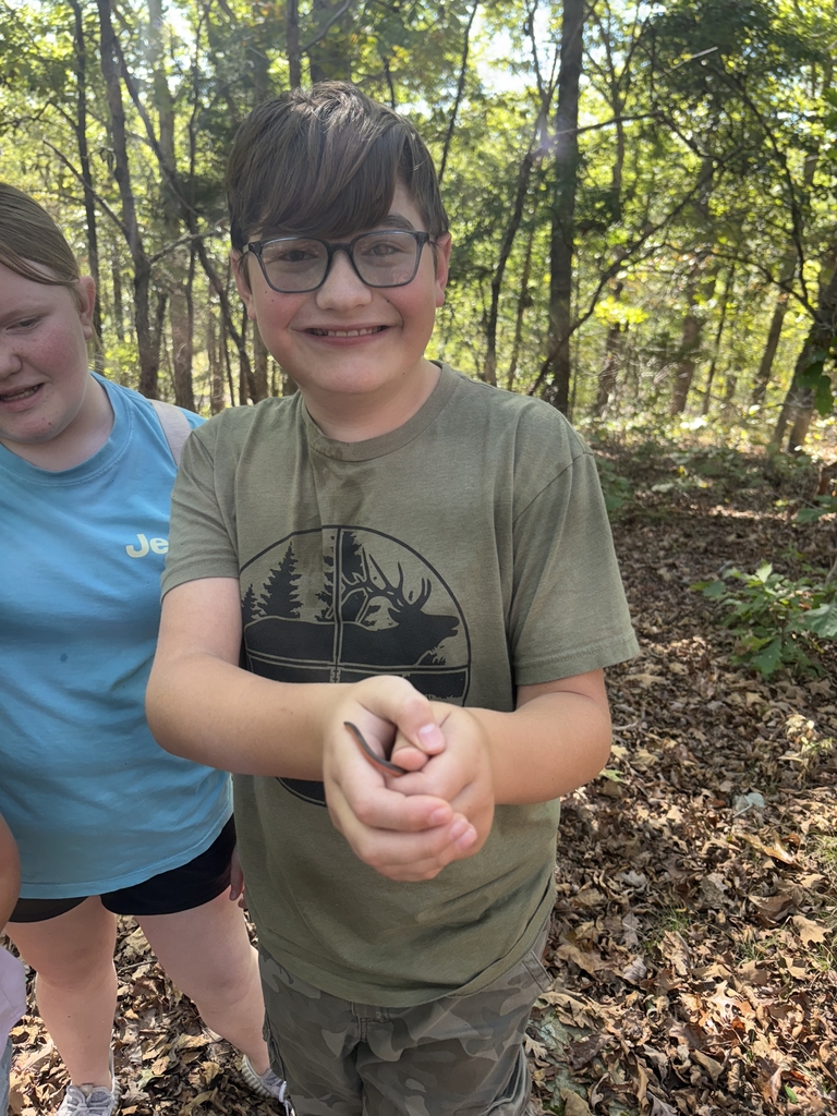 young boy wearing a green shirt holding a small snake