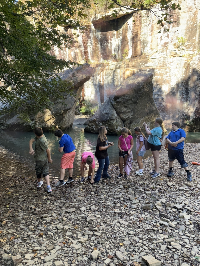 group of 8 junior high students standing on rocks in front of a large rock formation