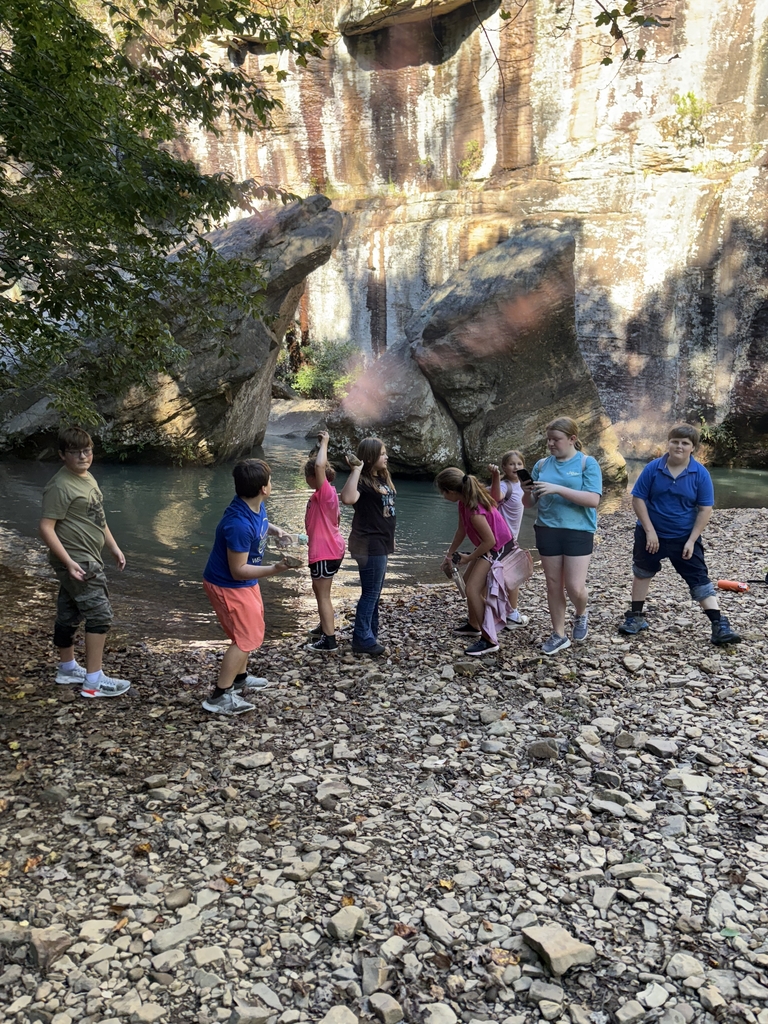 group of 8 junior high students standing on rocks in front of a large rock formation