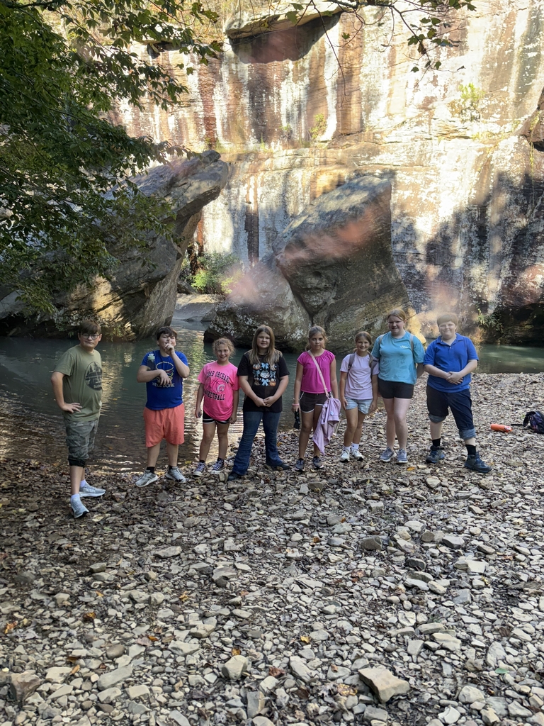 group of 8 junior high students standing on rocks in front of a large rock formation