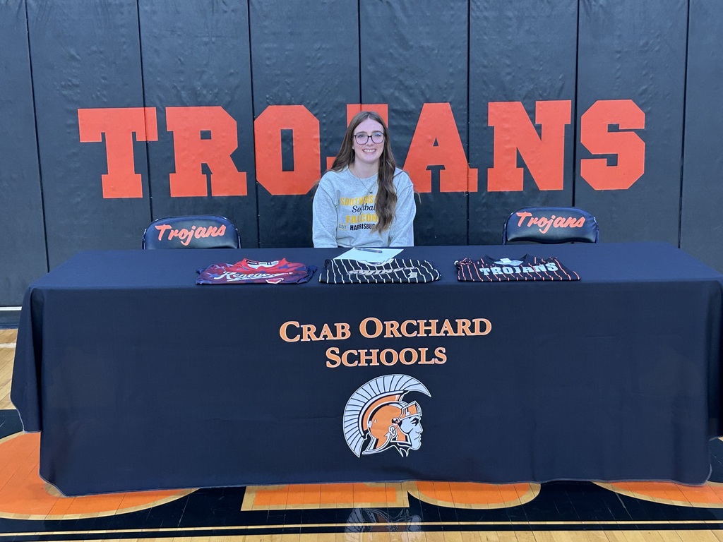 Player in a gray shirt sitiing behind a black table 