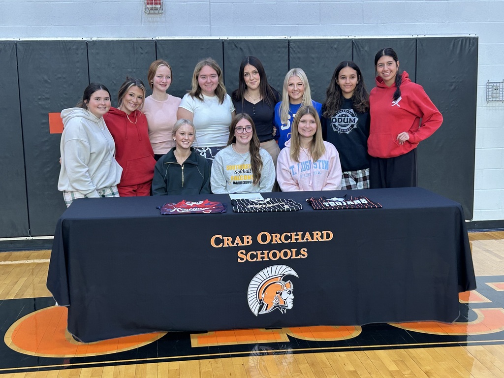 Softball girls sitting behind a table for a singing black table cloth and different color clothes 