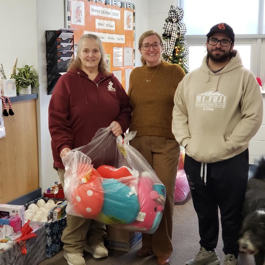 3 adults standing holding Christmas presents