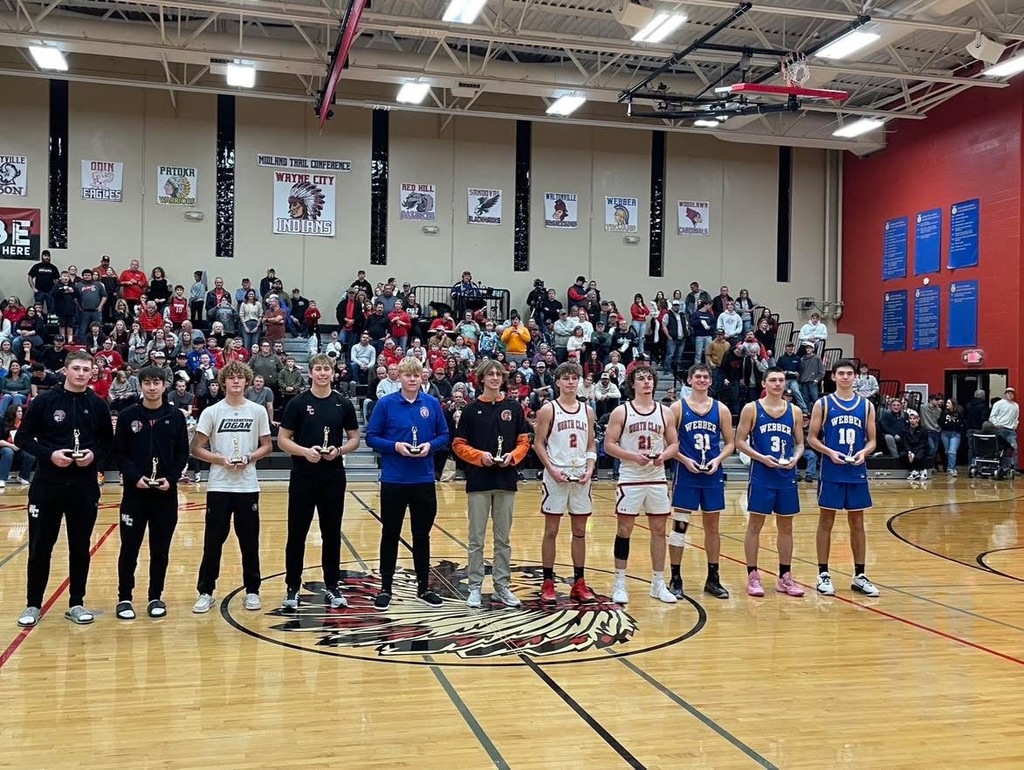 Boys standing in line holding trophies for all tournament team. 