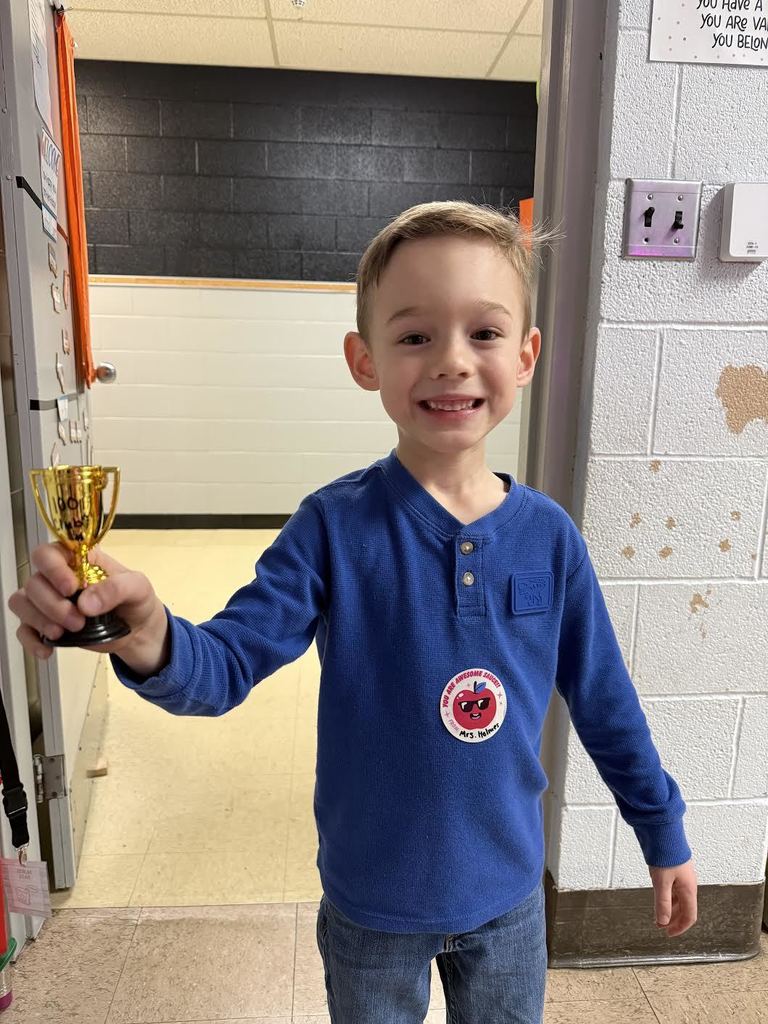 Kindergarten with brown hair holding a plastic trophy