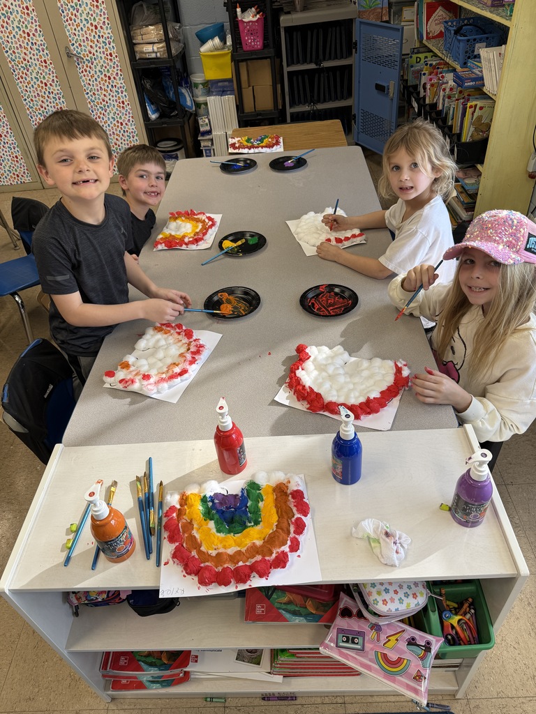 elementary students sitting at a table creating rainbows