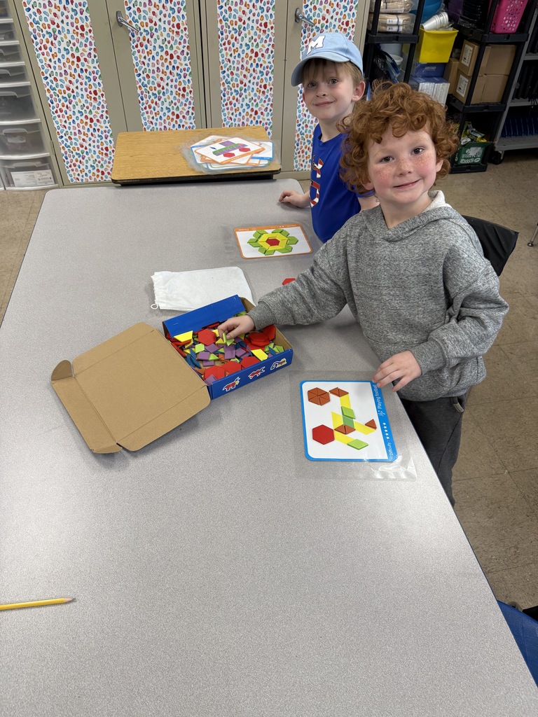 two elementary boys sitting at a table with tangrams