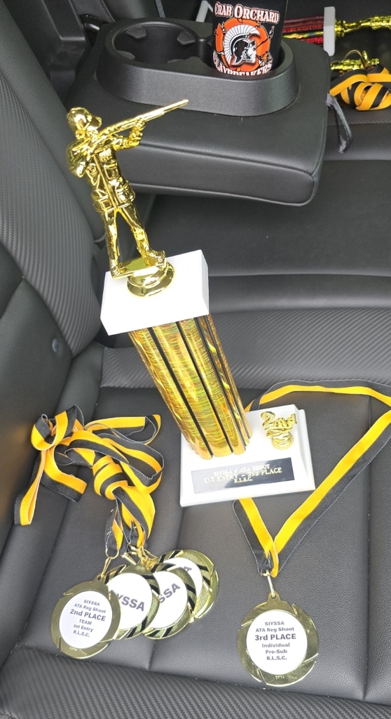 3rd place trophy and 2nd place medals sitting on a black car seat