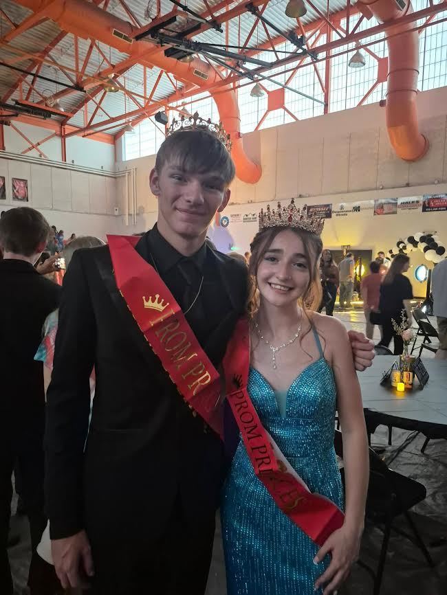 prom prince and prom princess standing next to each other wearing a red sash