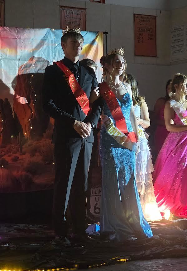 prom prince and prom princess standing next to each other wearing a red sash