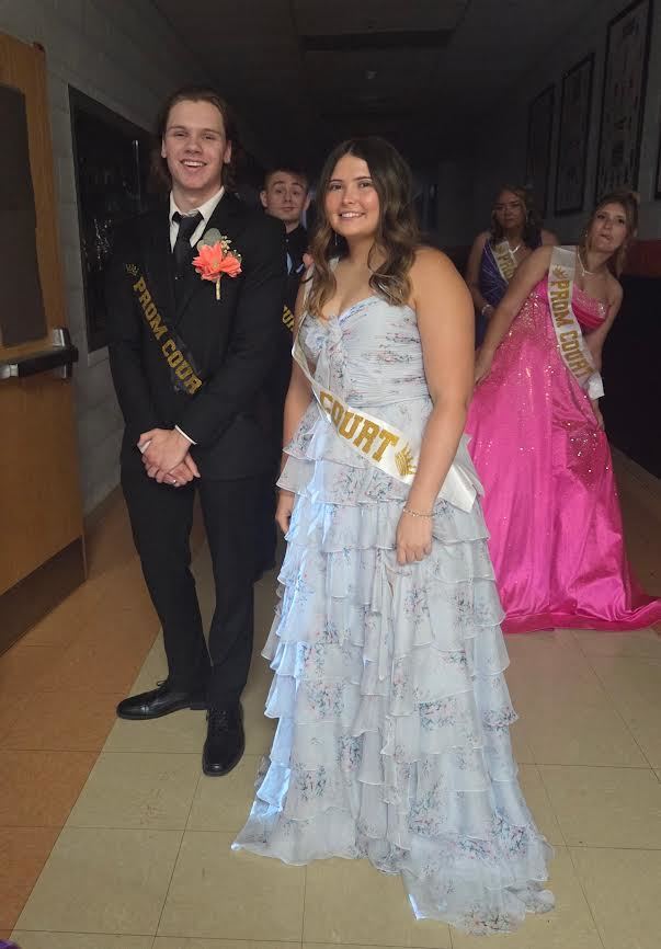 prom king and prom queen standing next to each other wearing a white sash