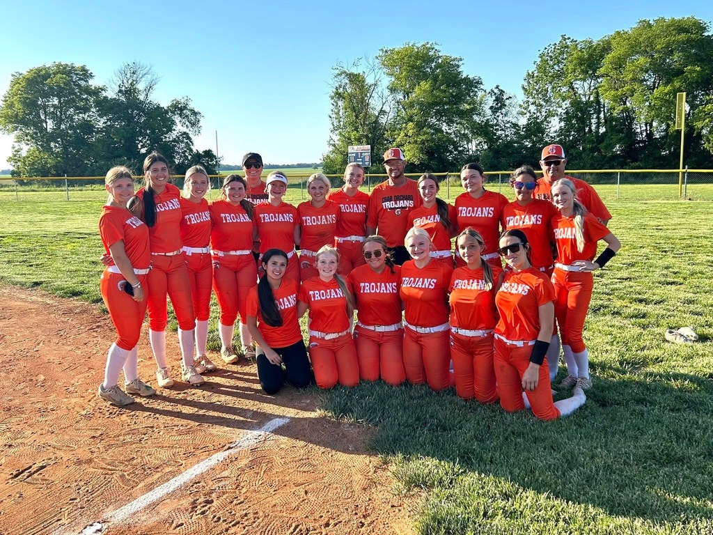 high school girls softball team wearing orange standing and kneeling on grass