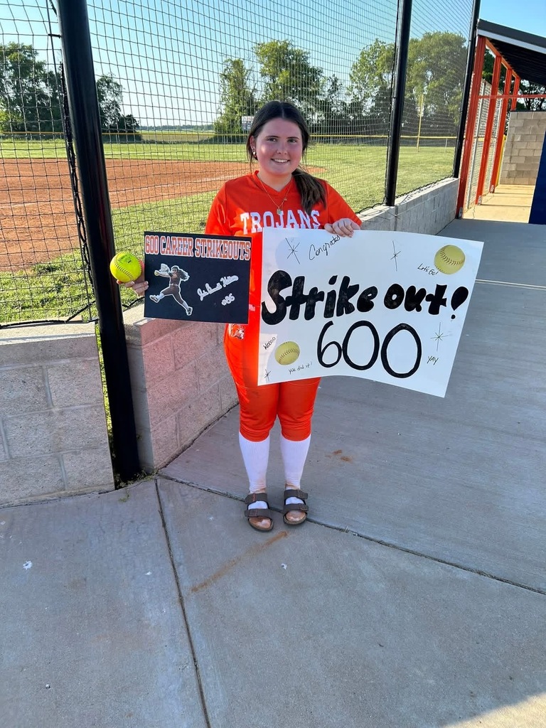 high school softball girl wearing orange holding a sign for 600 strikeouts