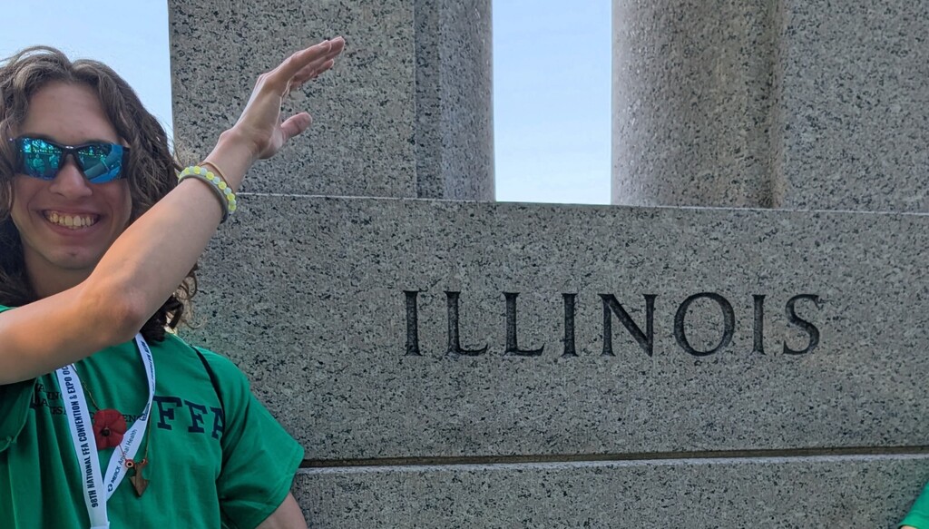Young man wearing a green t-shirt standing in front of an Illinois monument